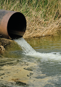 Wastewater pouring out of a tube into a river.