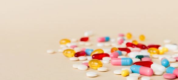 Various medications, set on a light pink background. 