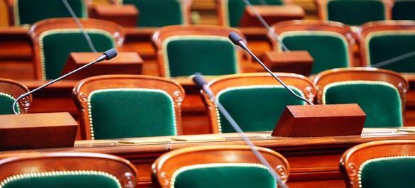Collection of green and wooden seats with three speaker microphones. 